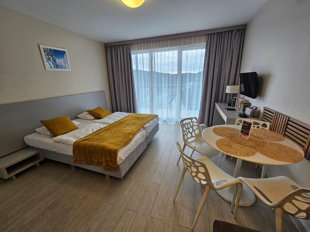 a bedroom with a bed and a table and chairs at Czarna Góra Resort, Apartament z widokiem na góry, Stubai in Biała Woda