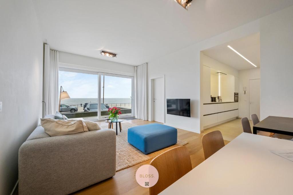 a living room with a couch and a table at Osean by BLOSS luxe appartement met frontaal zeezicht, binnenzwembad en parking in Middelkerke