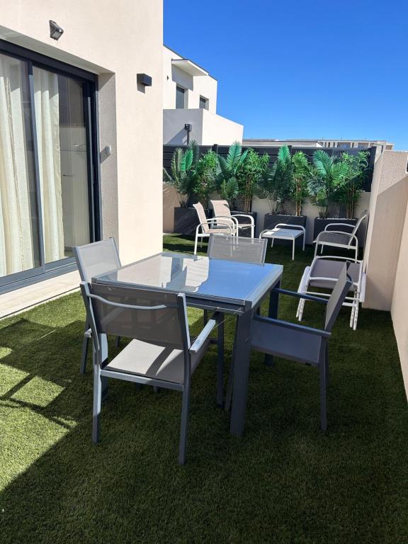 une table et des chaises sur une terrasse avec pelouse dans l'établissement Casita: votre oasis de détente, à Sérignan
