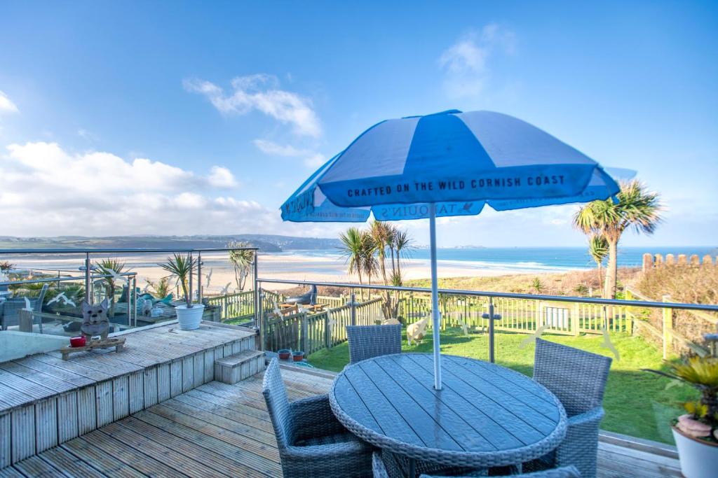 einen Tisch mit Sonnenschirm auf einer Terrasse mit Strand in der Unterkunft Beach View House - Self Catering Hayle, St Ives Bay Cornwall in Hayle