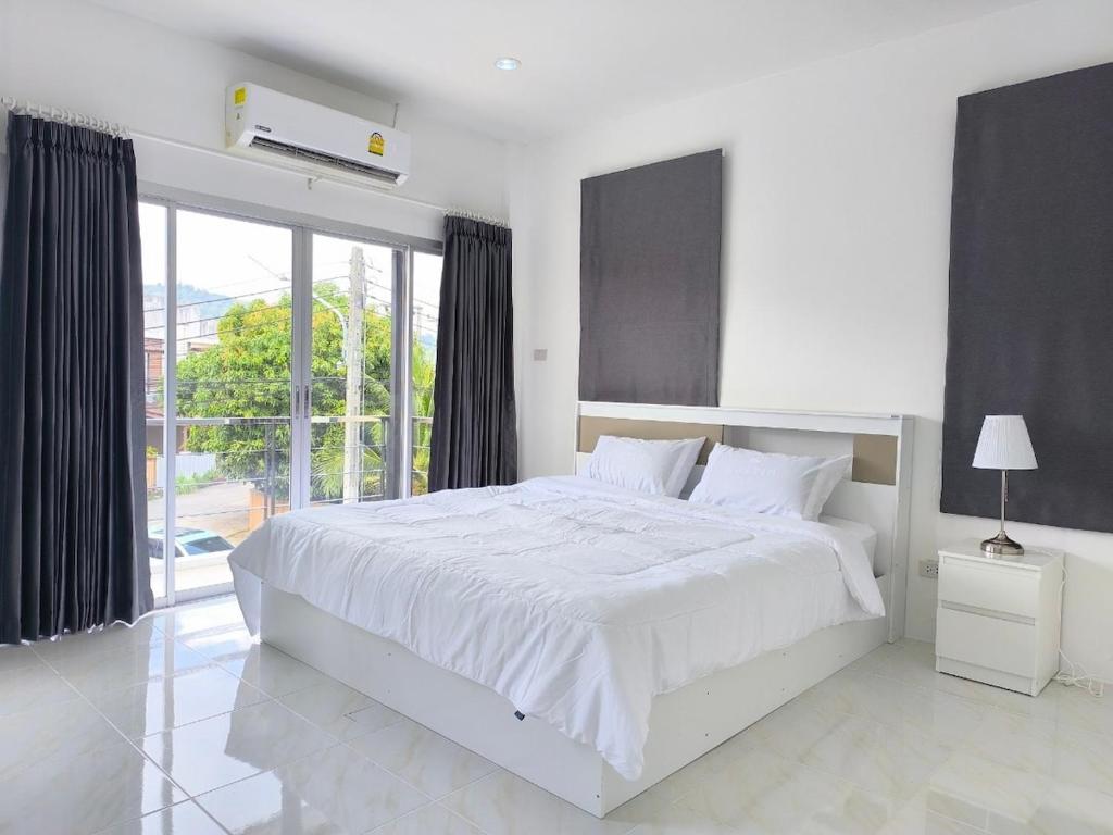 Home Phuket Andaman 3BR في Ban Klang: غرفة نوم بيضاء مع سرير كبير ونافذة