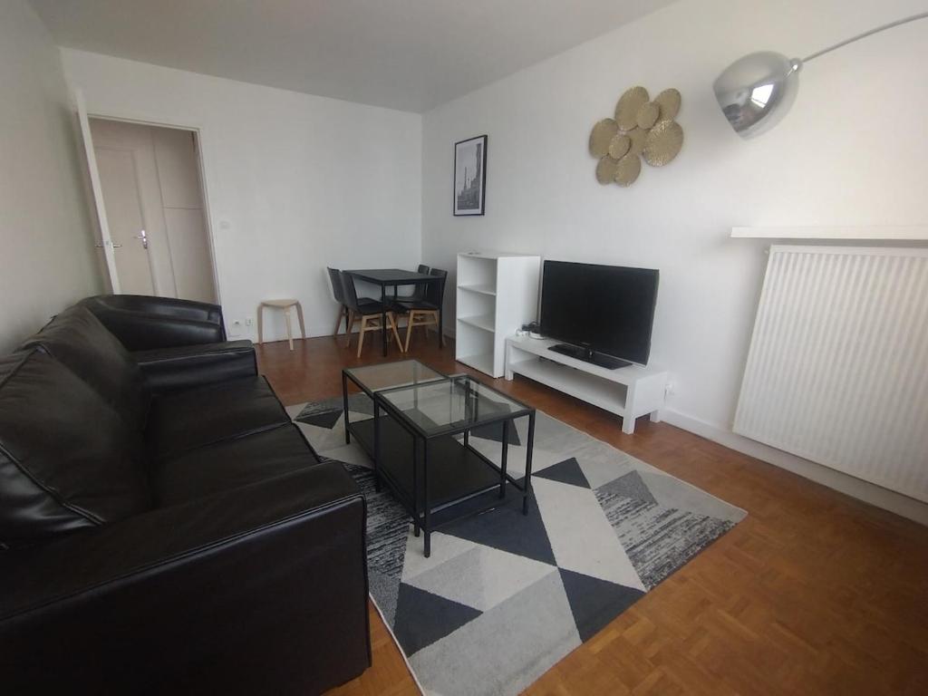un salon avec un canapé en cuir noir et une télévision dans l'établissement Cozy 1 bedroom Apartment La Defense, à Courbevoie