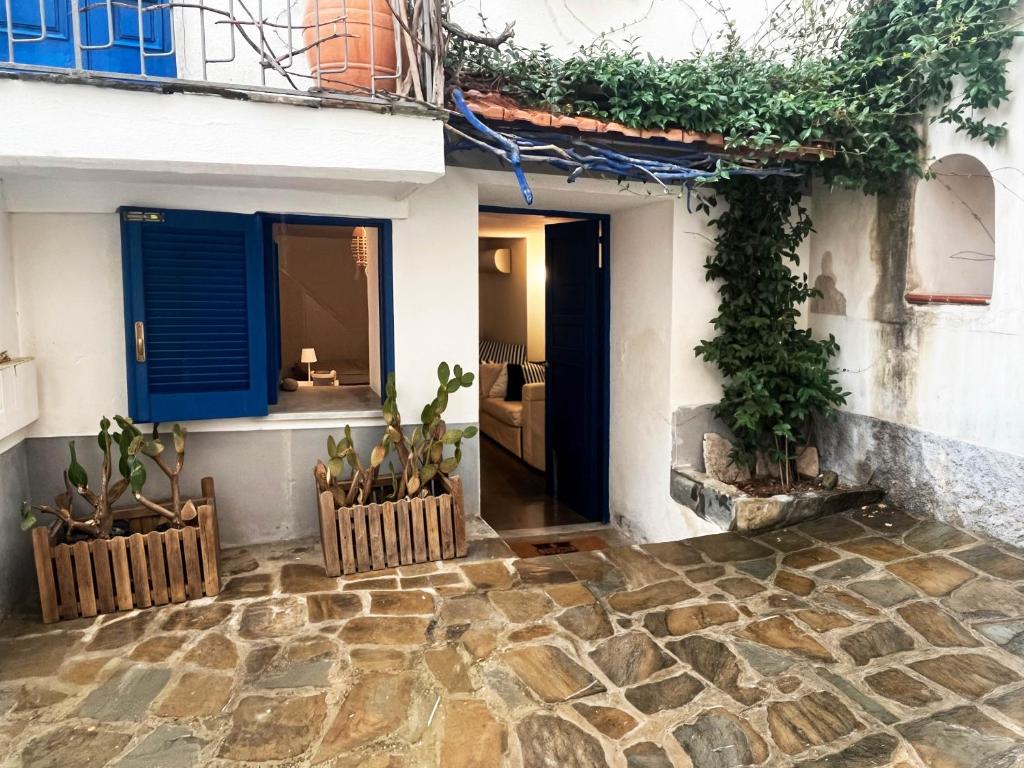 a house with blue shutters and plants in a courtyard at Casa Magica Ogliastro in San Marco di Castellabate
