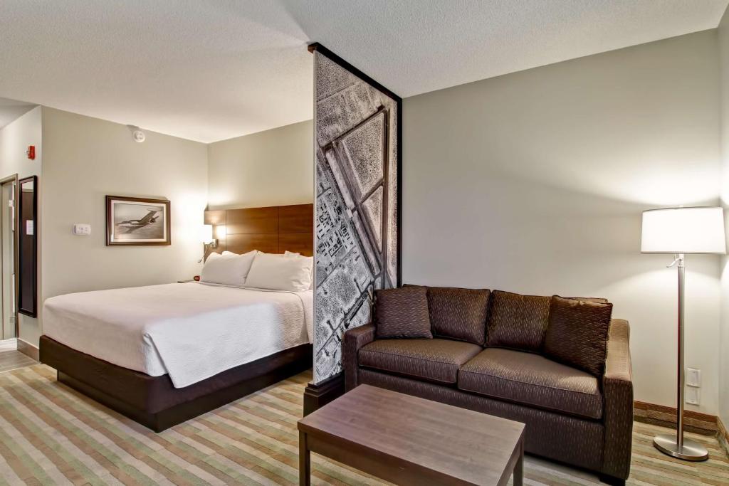 a hotel room with a bed and a couch at Best Western London Airport Inn & Suites in London