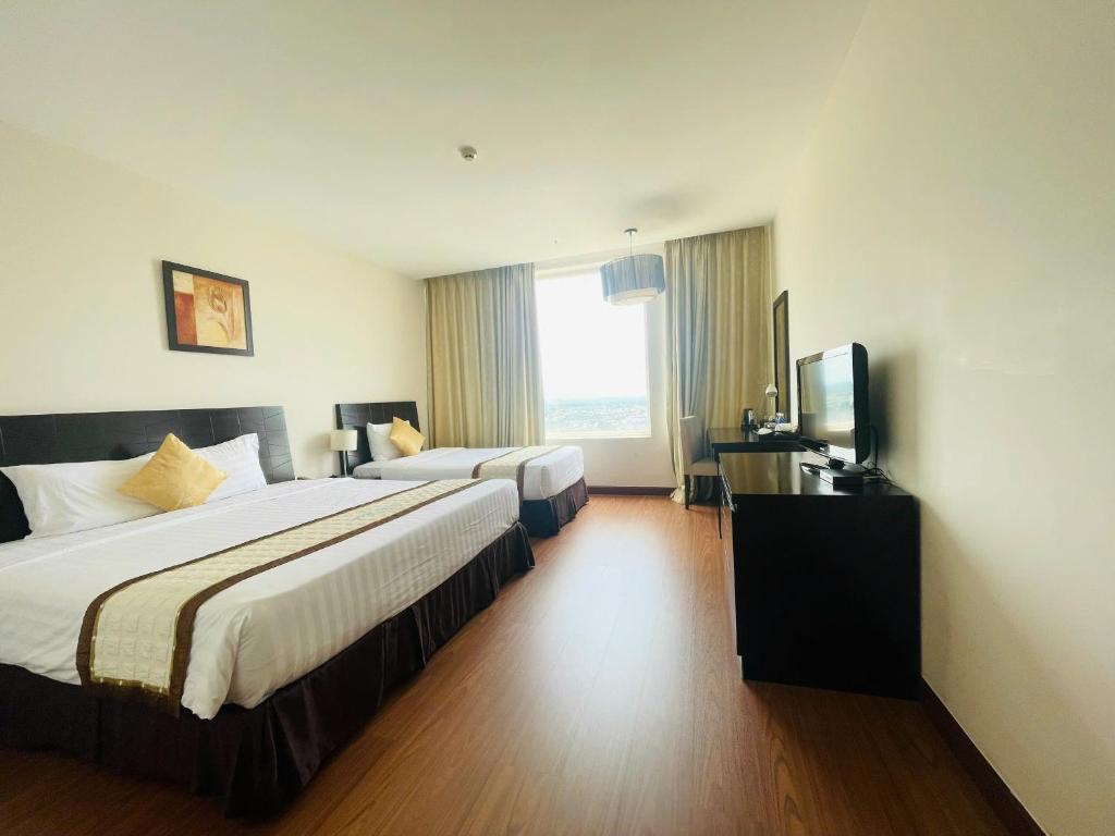 a hotel room with two beds and a television at Sai Gon Ban Me Hotel in Buon Ma Thuot