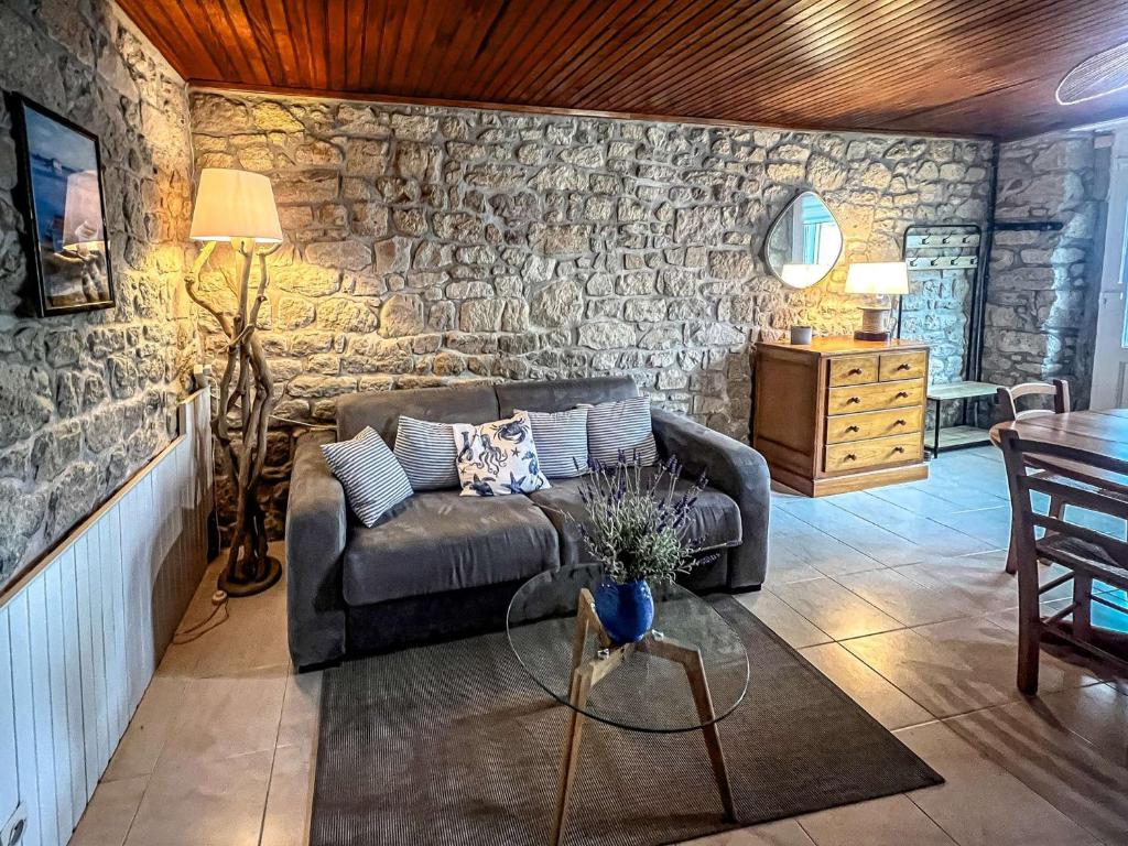 un salon avec un canapé et un mur en pierre dans l'établissement Étel - Maison rénovée 3 pièces cosy avec WiFi - FR-1-479-224, à Étel