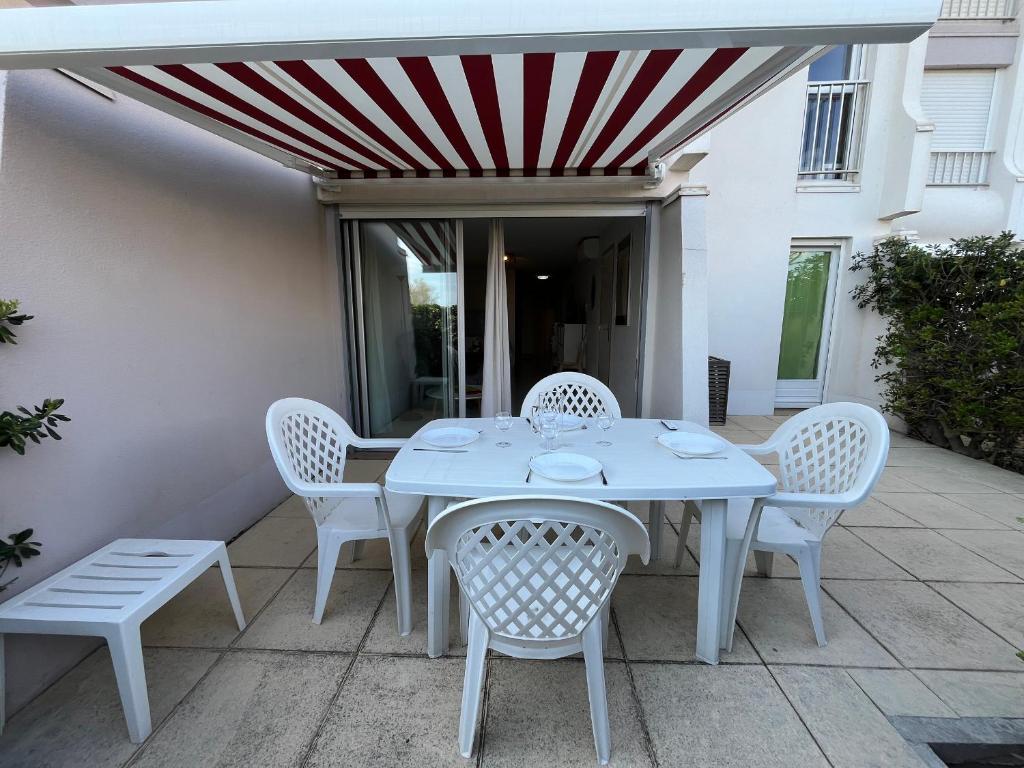 une table blanche et des chaises sur une terrasse dans l'établissement Appartement 2P cabine, face plage, clim, parking privatif - FR-1-338-609, à Sète