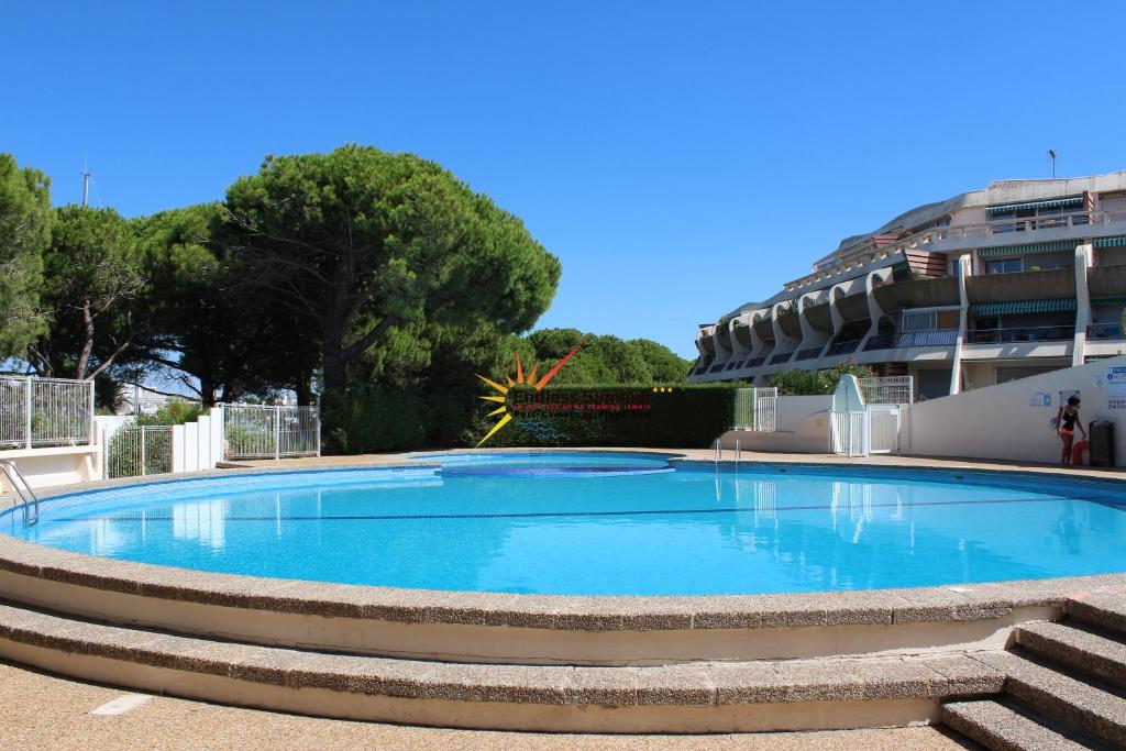 une grande piscine bleue dans un immeuble dans l'établissement Studio 0233, Port Camargue, Piscine, WiFi, Parking, 2 personnes, au Grau-du-Roi