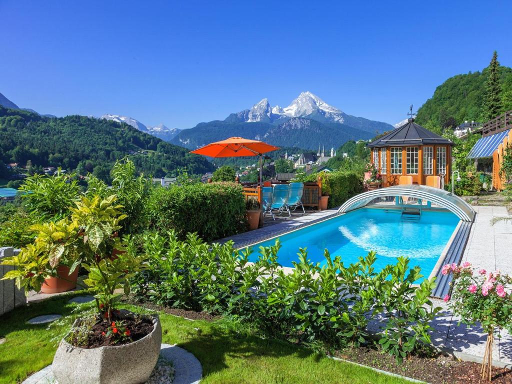 una piscina en un jardín con montañas al fondo en Ferienwohnungen Scheifler en Berchtesgaden