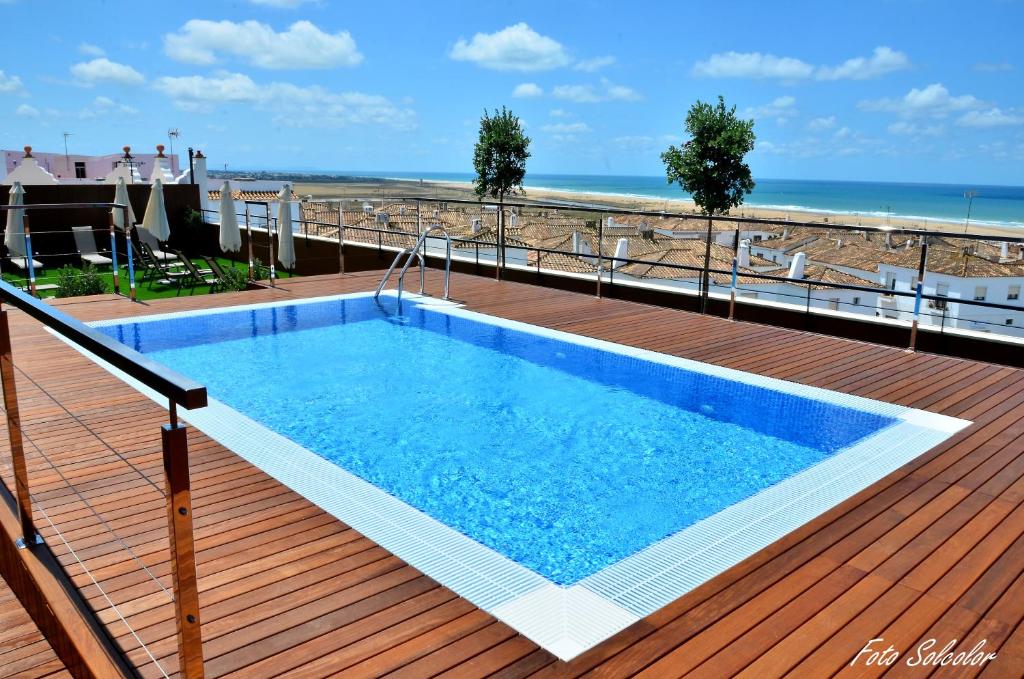 a swimming pool on a deck next to the beach at Hotel y Apartamentos Conilsol in Conil de la Frontera