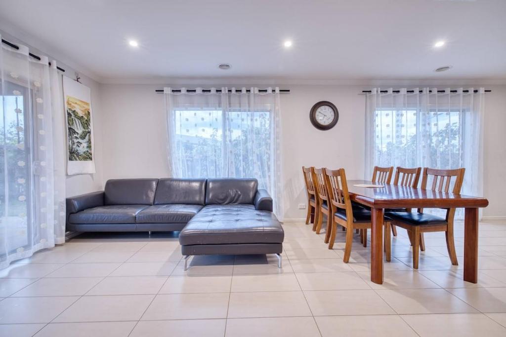 a living room with a couch and a table and chairs at Warm and romantic cottage-4Bed-9guests in Tarneit
