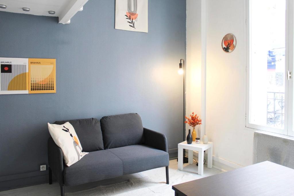 un salon avec un canapé et un mur bleu dans l'établissement Beautiful mezzanine studio in the city center, à Saint-Ouen
