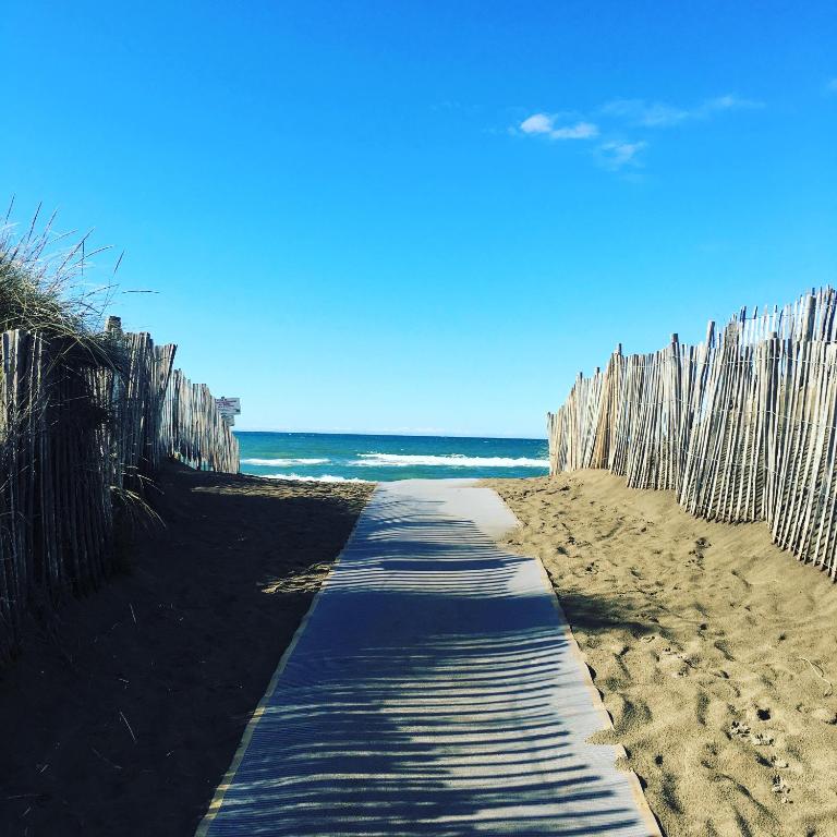 un chemin sur une plage avec une clôture en bois dans l'établissement Studio 0237 Port Camargue, Piscine, Climatisation, 2 personnes, au Grau-du-Roi
