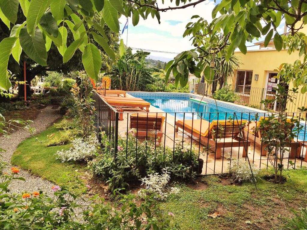 a swimming pool in a garden with a fence at Descanso las Tres Marias Apart Hotel in Villa Carlos Paz