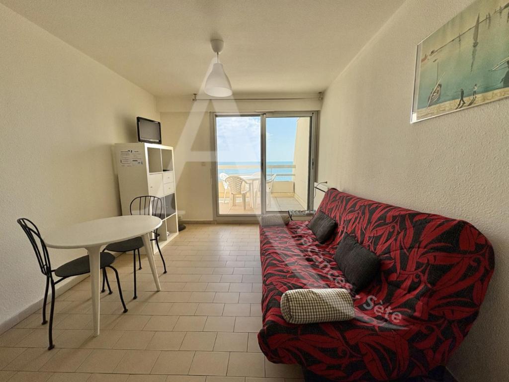 un salon avec un canapé rouge et une table dans l'établissement Residence front de mer studio cabine 4 personnes, à Sète