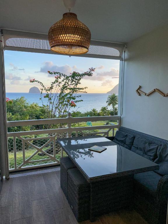 a living room with a large window with a view of the ocean at Studio vue mer avec piscine - Le Diamant in Le Diamant