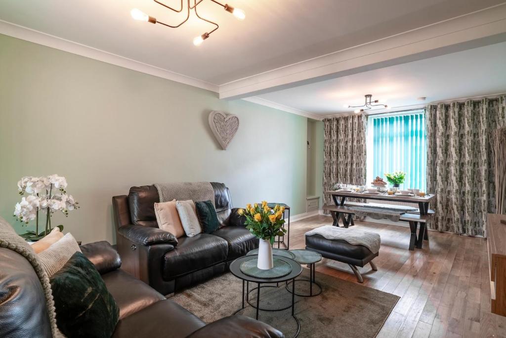 ein Wohnzimmer mit Ledermöbeln und einem Klavier in der Unterkunft Ty Gwyrdd, 3 bedroom house, sleeps 7, Near Bike Park Wales in Abercanaid