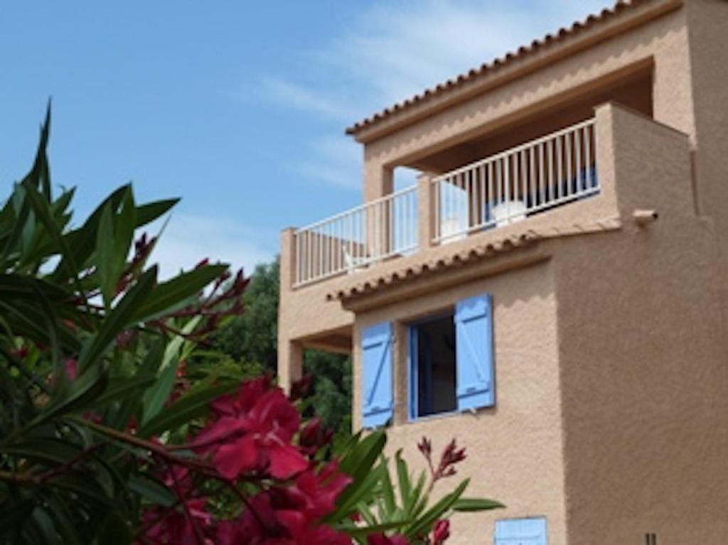 - un bâtiment avec un balcon et des fleurs devant dans l'établissement Résidence U LATONU, à Porto-Vecchio