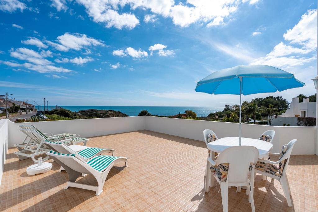 a patio with a table and chairs and an umbrella at Vivenda Estrela do Mar in Carvoeiro