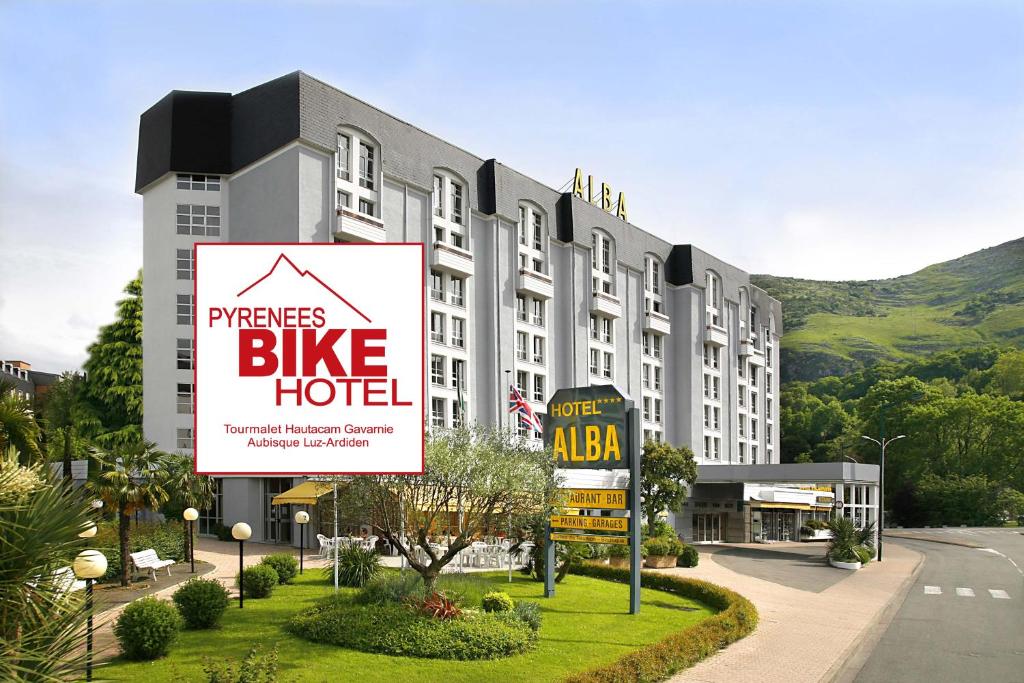 un gran edificio con un cartel para un hotel de bicicletas en Hôtel Alba en Lourdes