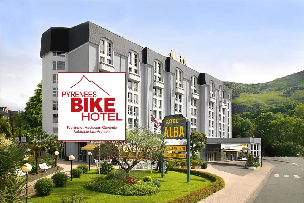 un grand bâtiment avec un panneau indiquant un hôtel pour vélos dans l'établissement Hôtel Alba, à Lourdes