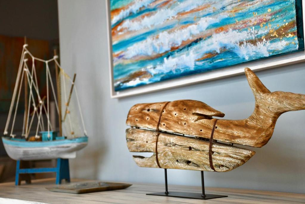a wooden statuette of a whale in front of a painting at Aquamarine - Gemstone Getaway in Vale do Lobo