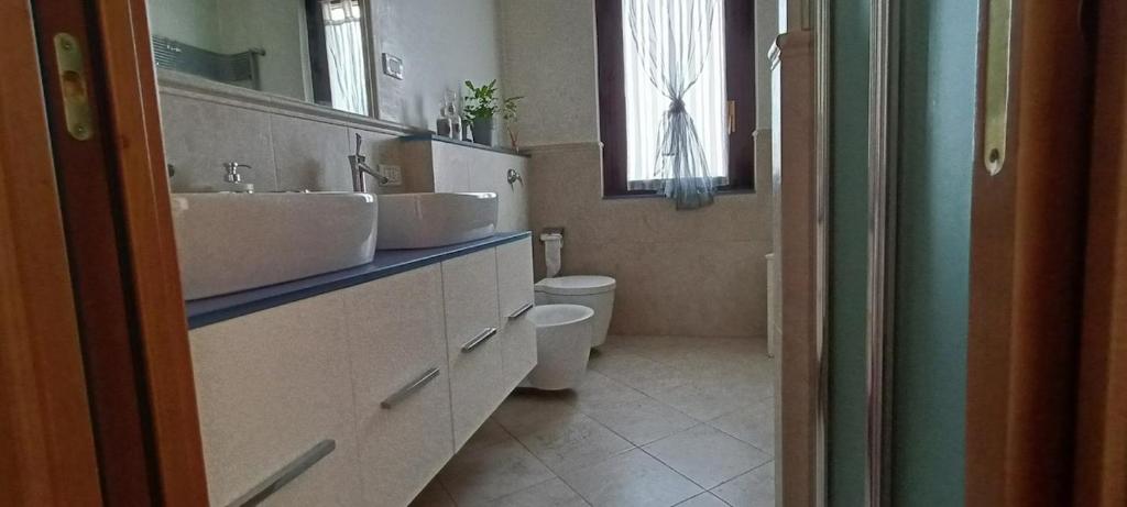 a bathroom with two sinks and a toilet and a window at Casa Vanessa Appartamento in Villa in Pieve Emanuele