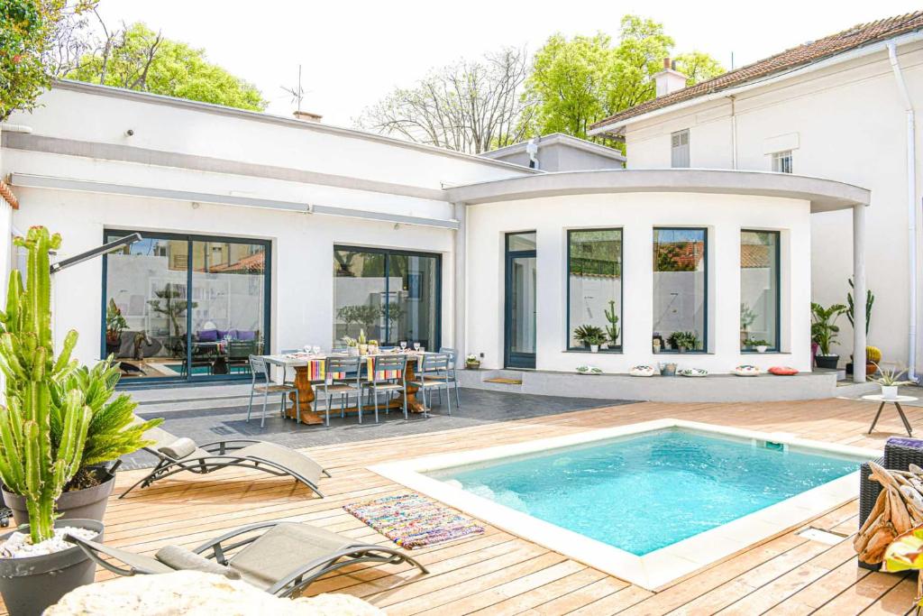 une maison avec une piscine sur une terrasse en bois dans l'établissement La Luminy - Villa moderne avec piscine et parking, à Marseille