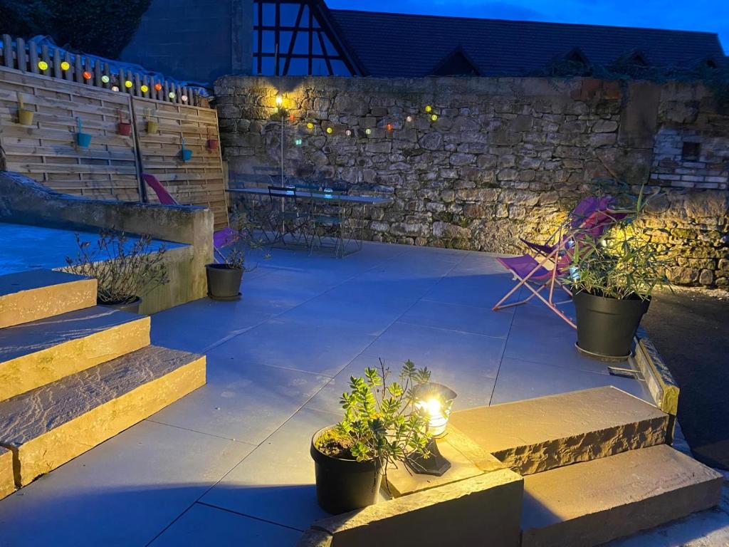 un patio con piante in vaso e scale di notte di La Petite Maison de la Petite Vallée a Rott