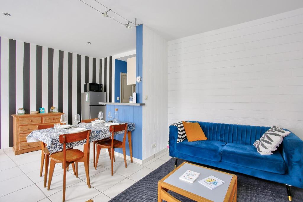 un salon avec un canapé bleu et une table dans l'établissement Ty Glaz - Jardin - Véranda - 800 m de la plage, à Dinard