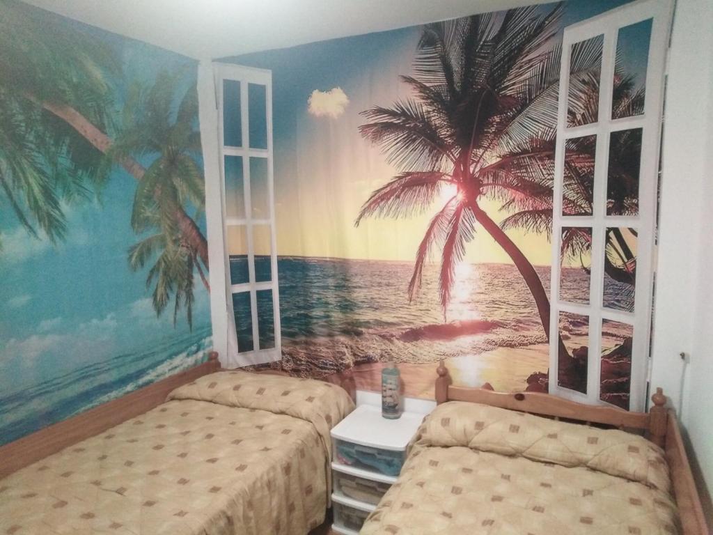 sypialnia z 2 łóżkami i malowidłem palmowym w obiekcie Camino Bed and Breakfast Corme w mieście Corme-Puerto