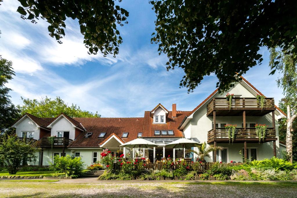 a large white house with a porch and balcony at Hotel-Pension Lindenhof in Boltenhagen