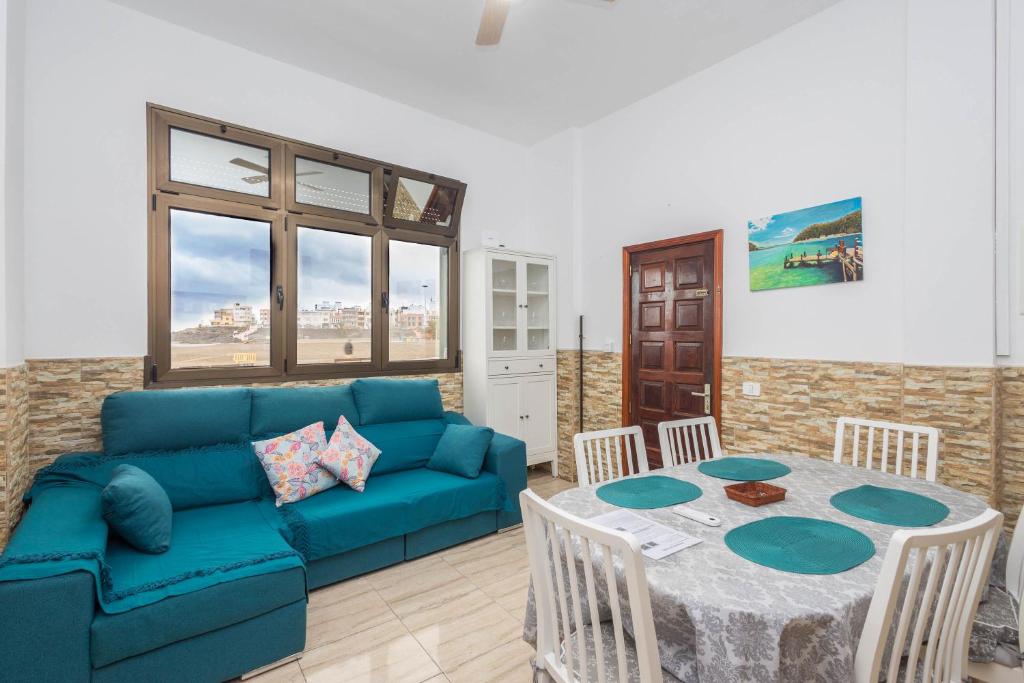 a living room with a blue couch and a table at Casa Playa Melenara in Melenara