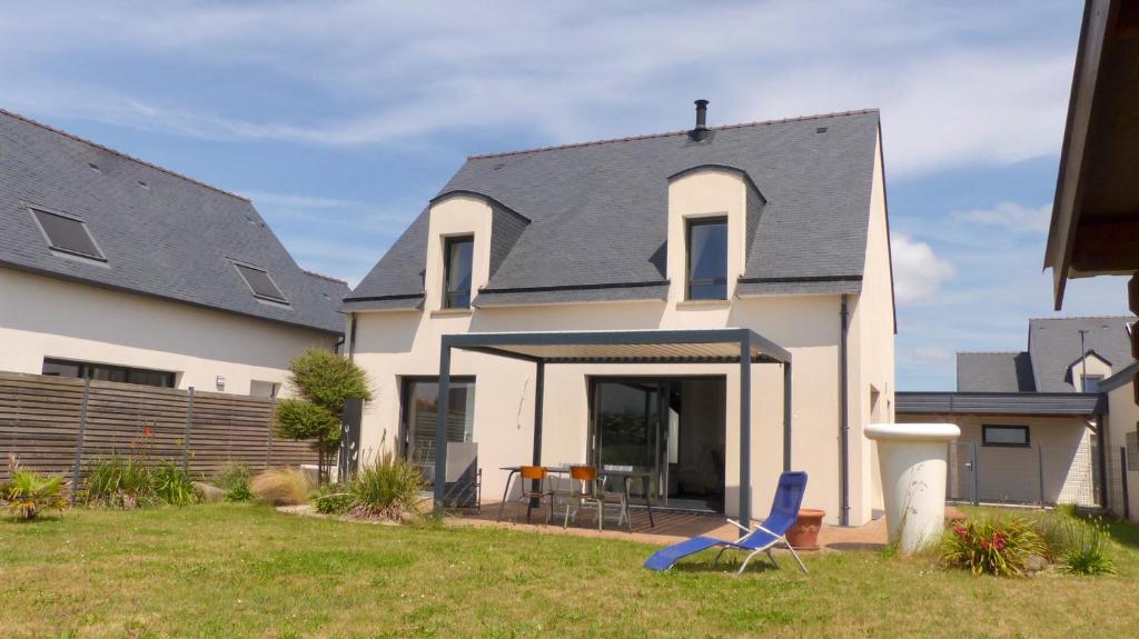une maison blanche avec une chaise bleue dans la cour dans l'établissement Confortable maison proche du centre-ville - Etel, à Étel