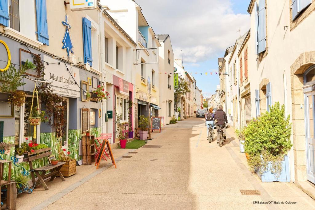 Un homme qui roule à vélo dans une rue avec des bâtiments dans l'établissement Ty Eglantines - confortable maison neuve proche des plages, à Étel