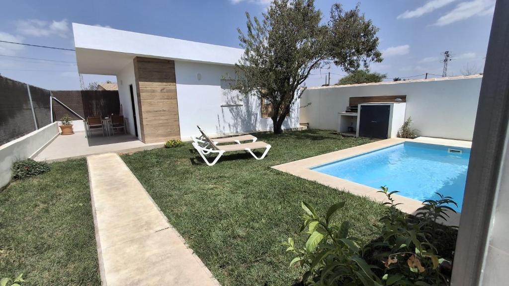 Un patio trasero con piscina y una casa. en Passive House con piscina y jardín privado, en Novo Sancti Petri