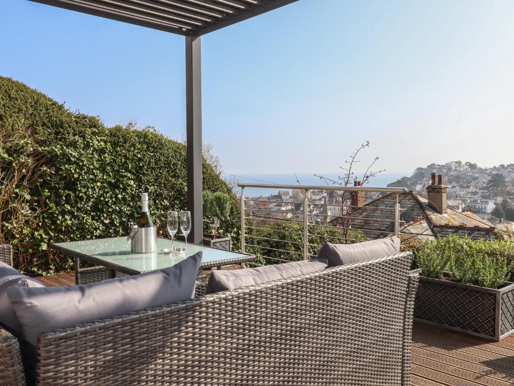 un patio con sillas de mimbre y una mesa de cristal en 15 Summerland Avenue, en Dawlish