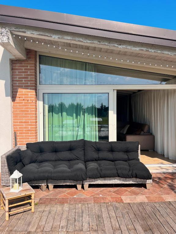 un grand canapé noir assis sur un patio dans l'établissement Cottage indipendente con piscina privata, à Masi San Giacomo
