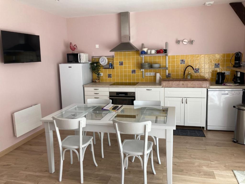 a kitchen with a glass table and white chairs at Maison Gille in Nuits-Saint-Georges