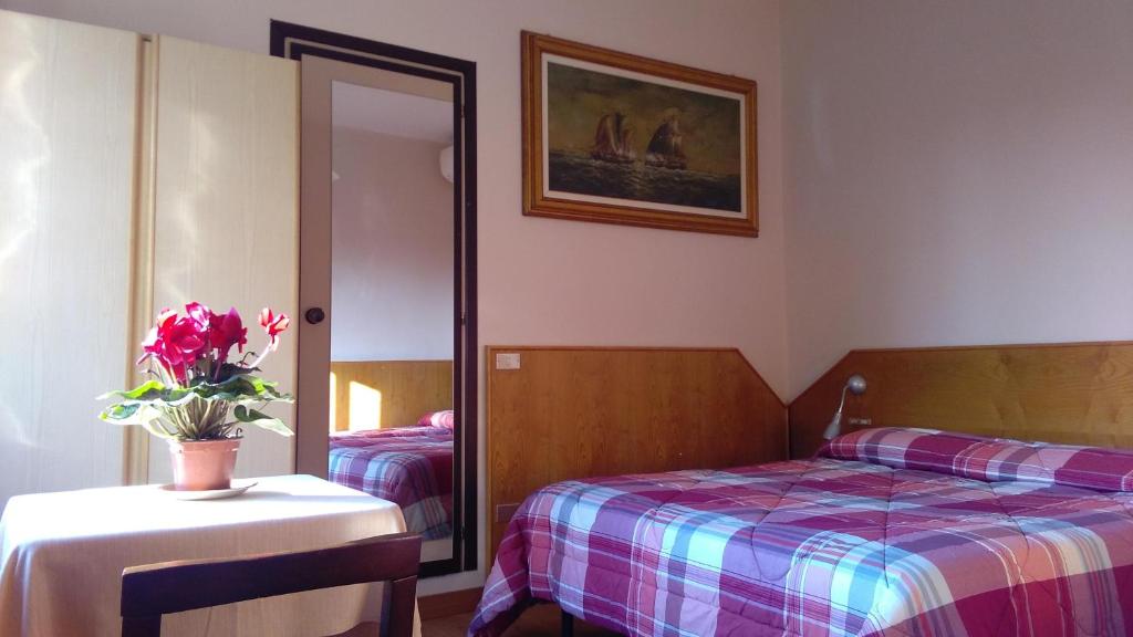 een slaapkamer met een bed en een tafel met een vaas met bloemen bij Affittacamere Giudici in Lentate sul Seveso