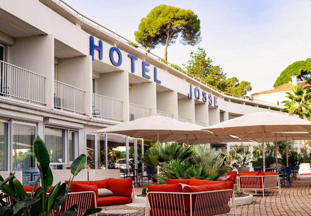 a hotel with chairs and umbrellas in front of it at Hôtel Josse in Antibes