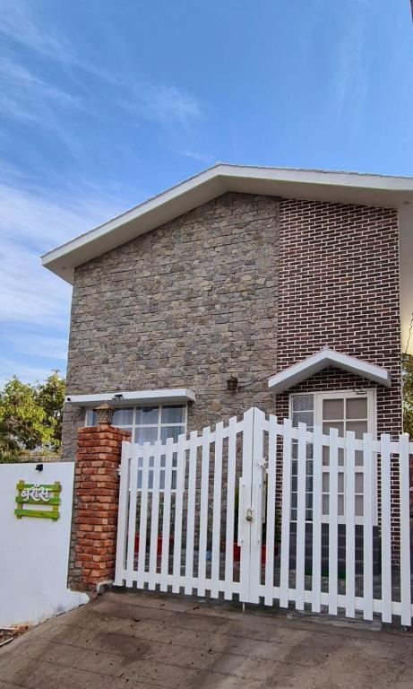 a white fence in front of a brick house at Buraans in Dehradun