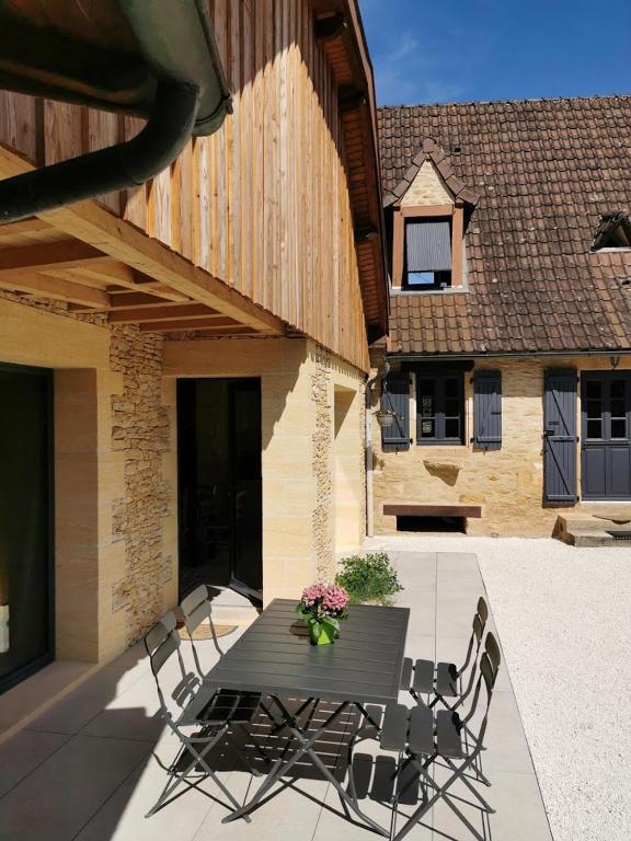 - une table noire avec des chaises et des fleurs sur la terrasse dans l'établissement Lou fredou, à Saint-Amand-de-Coly