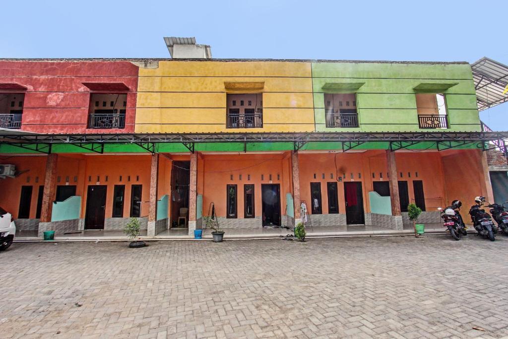 a colorful building with motorcycles parked in front of it at Hotel O Homestay Bang HajiNearLapangan Penujak ( Inen Gonggang) in Praya