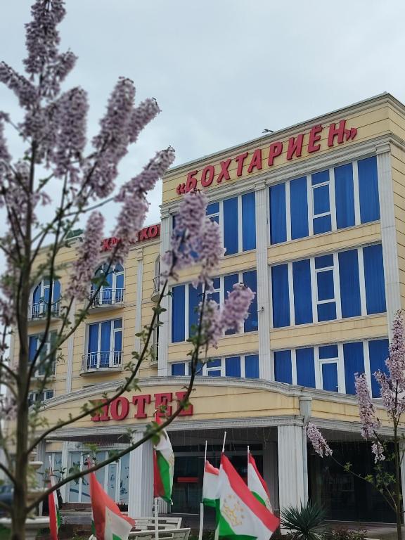 a building with a sign on the front of it at Bokhtariyon Hotel in Qŭrghonteppa