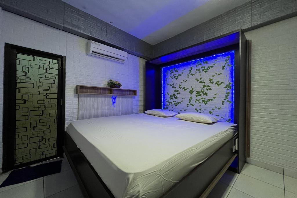 a bedroom with a white bed with a blue light at Hotel O Surya HotelNearTaman Anggrek Pkk Watansoppeng in Watansopeng