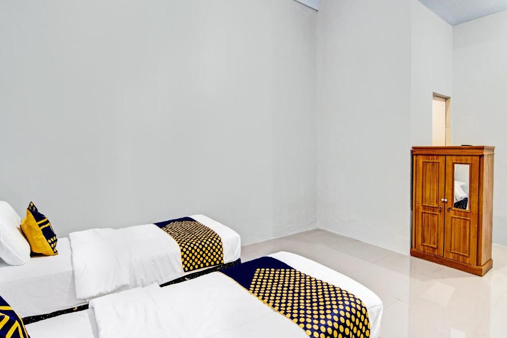 Zimmer mit 2 Betten und einem Holzschrank in der Unterkunft Hotel O Rumah Singgah Kinaya Syariah in Parit