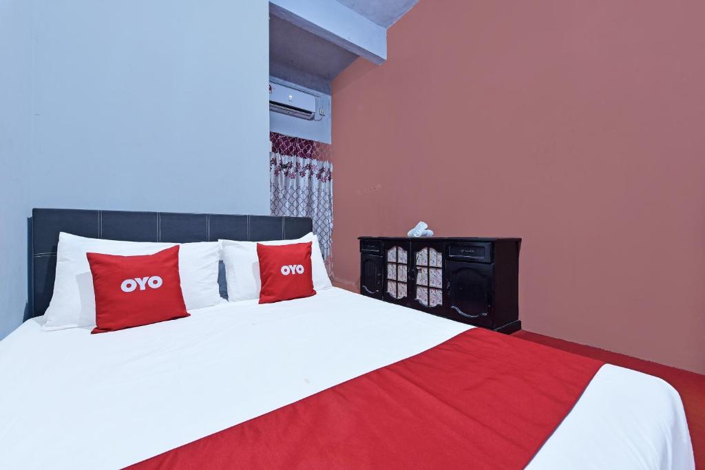 a bedroom with a bed with two red pillows at Capital O 90664 Rabi Hotel in Kota Bharu