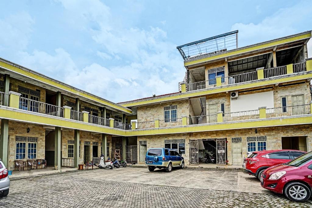 a large building with cars parked in a parking lot at OYO Life 91873 Nugraha Kost in Palembang