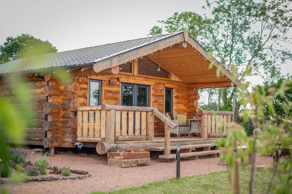 a log cabin with a porch and a porch swing at Willow - Tedstone Log Cabins in Bromyard